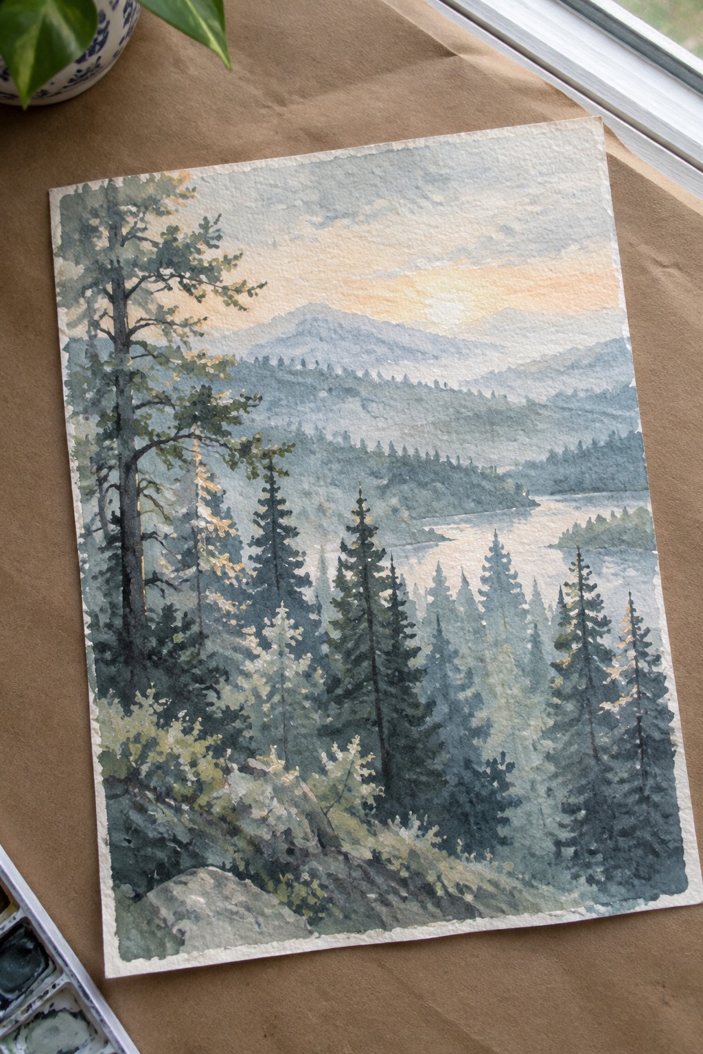Watercolor landscape of pine forest, misty mountains, and glowing sunset over water
