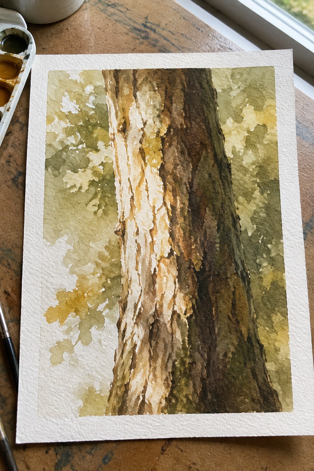 Watercolor painting of tree trunk in browns and greens beside paint palette and brushes